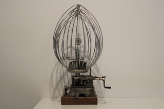 A whimsical steel sculpture combining a large whisk and pocketwatch